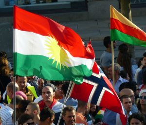 To ulike kurdiske flagg, og ett norsk, ved en kurdisk demonstrasjon på Jernbanetorget i Oslo. Foto: Hans Olav Arnesen. 